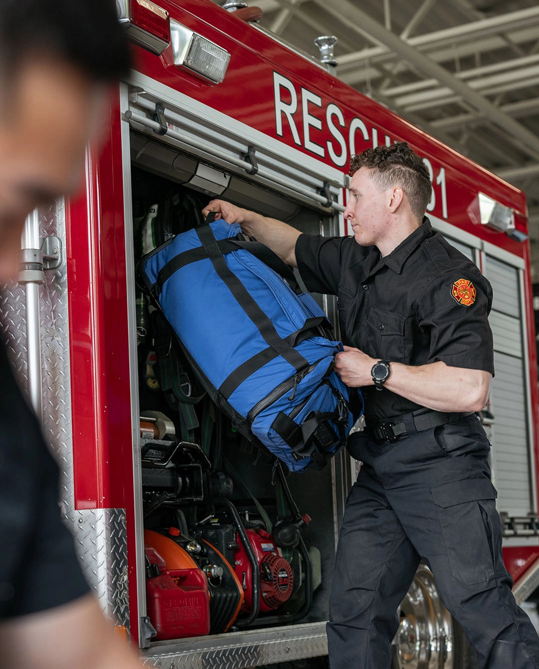 First responder loading the Thin Air Gear Pike rolling deployment bag into a fire rescue vehicle